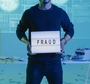 Man holding sign that says 'fraud'