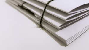 White paper folder stacked and bound together by black string